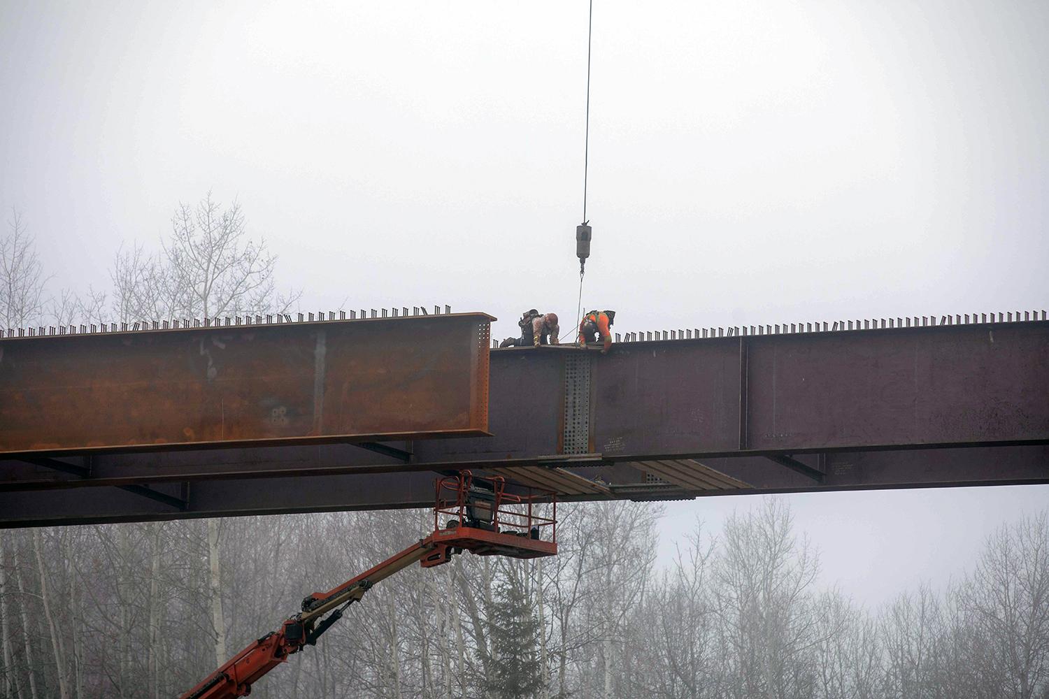 Workers install a girder splice plate to join two girders together on the Lynx Creek bridge along Highway 29 . | October 2021