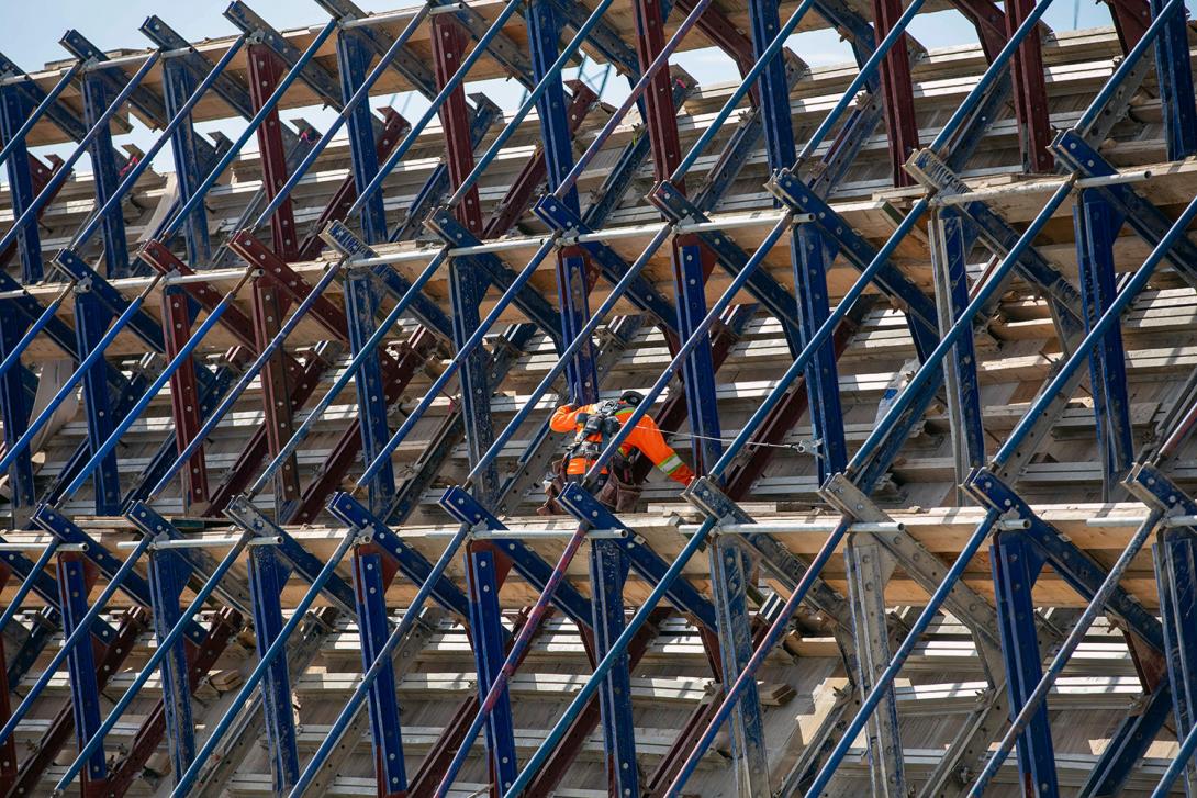 A worker installs roller-compacted concrete formwork between reinforced steel on the south face of the dam buttress. | June 2021