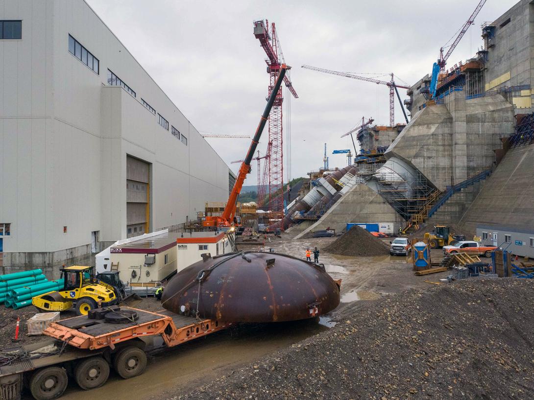 The first of four spiral case inlet bulkheads is delivered from the Voith warehouse at site to the powerhouse. | July 2021