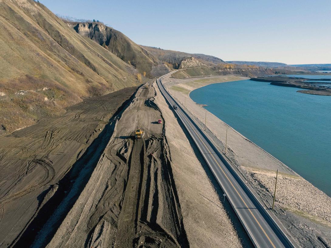 A bulldozer spreads material on the Lynx Creek Highway 29 embankment; the temporary detour is seen on the right. | October 2021