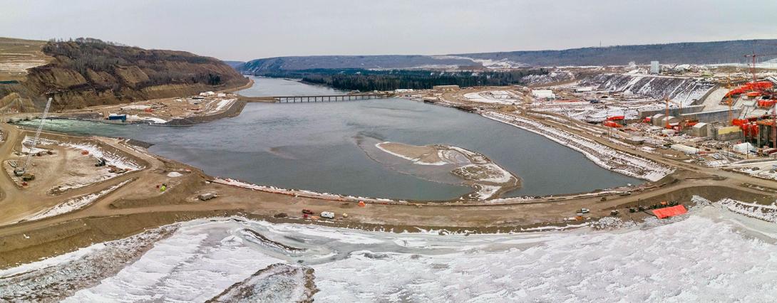 An aerial view of the downstream coffer dam. Both the upstream and downstream cofferdams have been installed across the river and interlocking steel pile walls have been completed. Pumping out of the water between the cofferdams is currently underway and expected to continue through February 2021. | January 2021