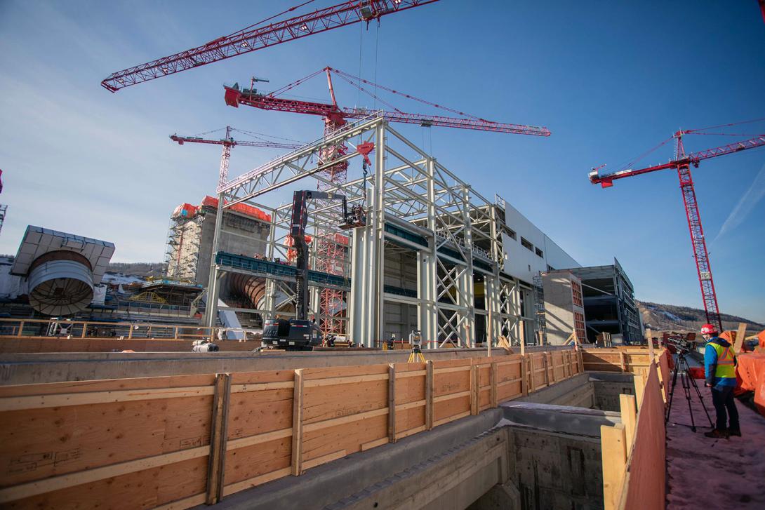 Powerhouse steel superstructure construction. The powerhouse construction also includes concrete placements at the powerhouse, intakes and spillway, installation of penstock segments. | February 2021