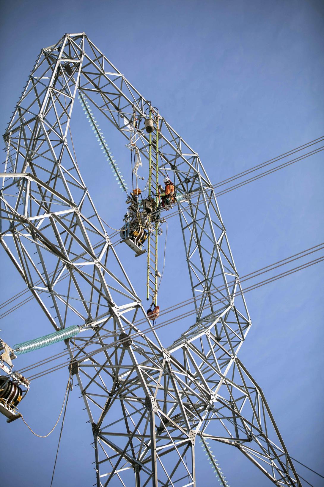 Attaching the centre-phase conductor and installing corona rings on a transmission tower. | February 2022