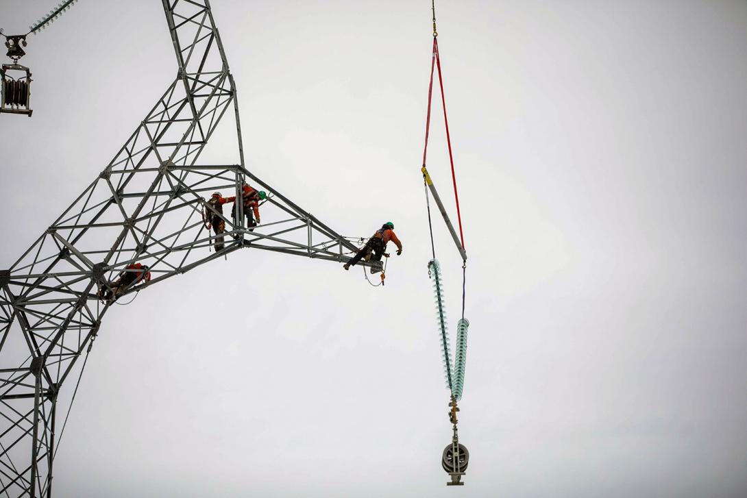 A powerline technician attaches the cable to the insulator assembly. |January 2022