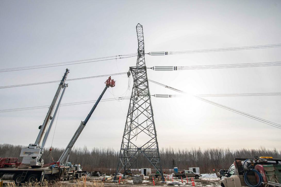 Linemen are moving into position to dead-end the transmission line to the tower. | February 2022