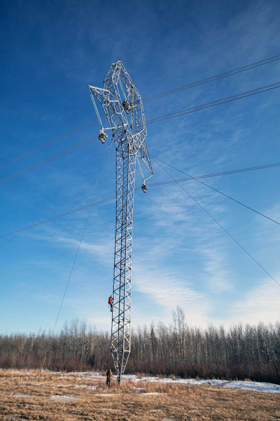 Workers climbing a guyed tower to attach the conductors. | February 2022