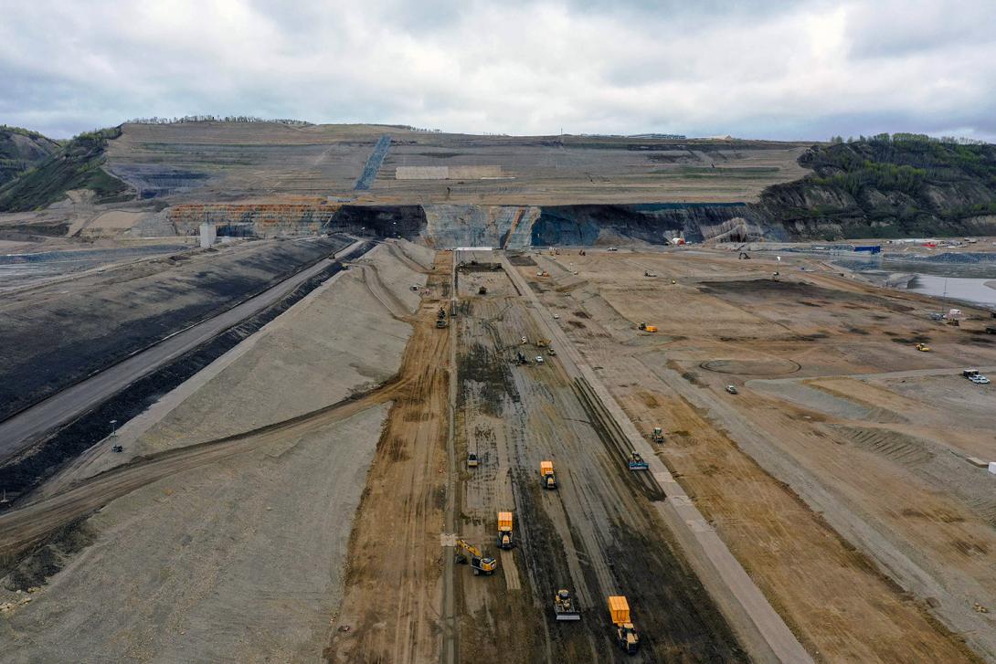 At the dam core, near the upstream cofferdam, large orange pneumatic compactors crush glacial till which is then spread by bulldozers. | May 2022