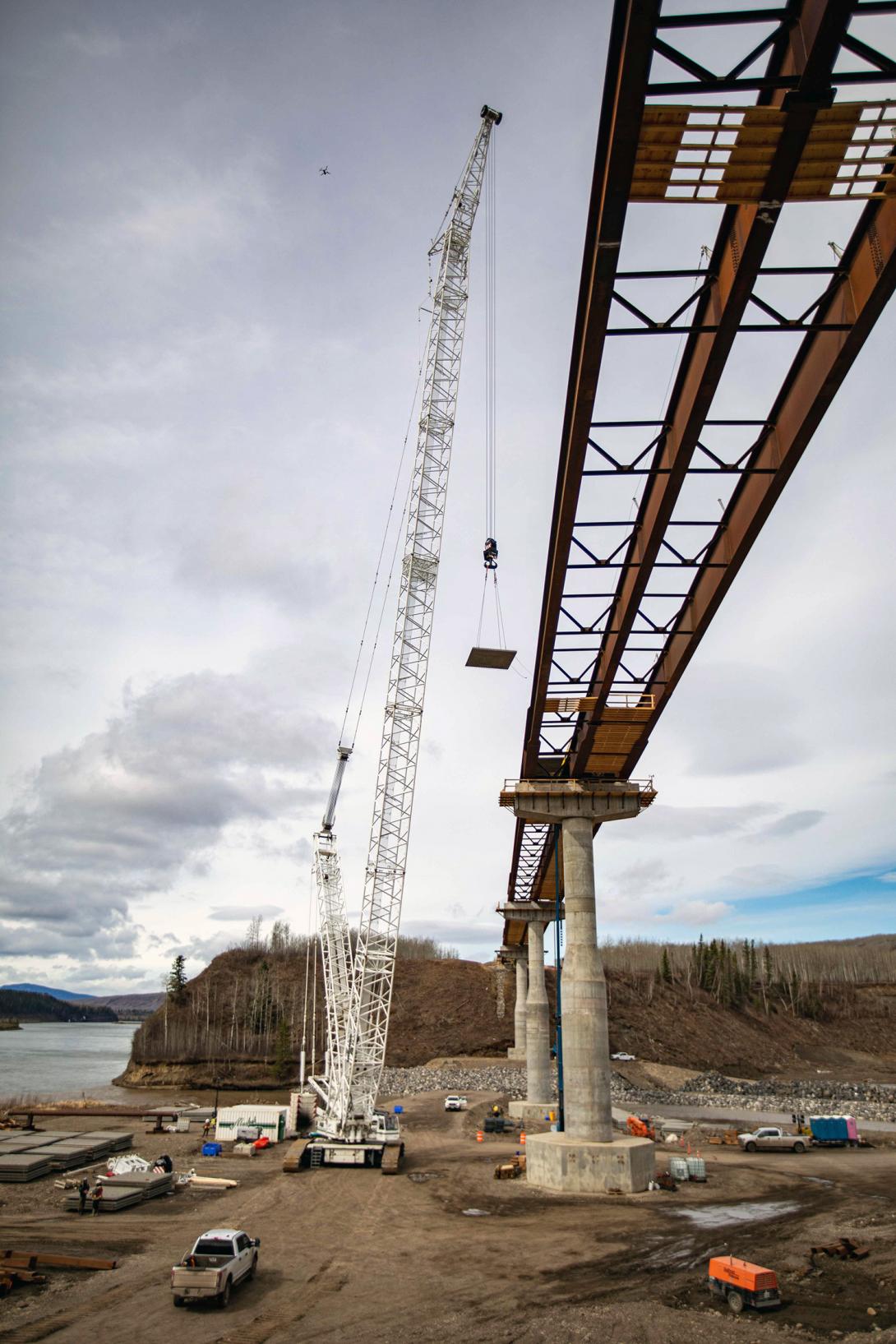 A pre-cast concrete panel is lifted into place between piers two and three on the Farrell Creek bridge. | May 2022