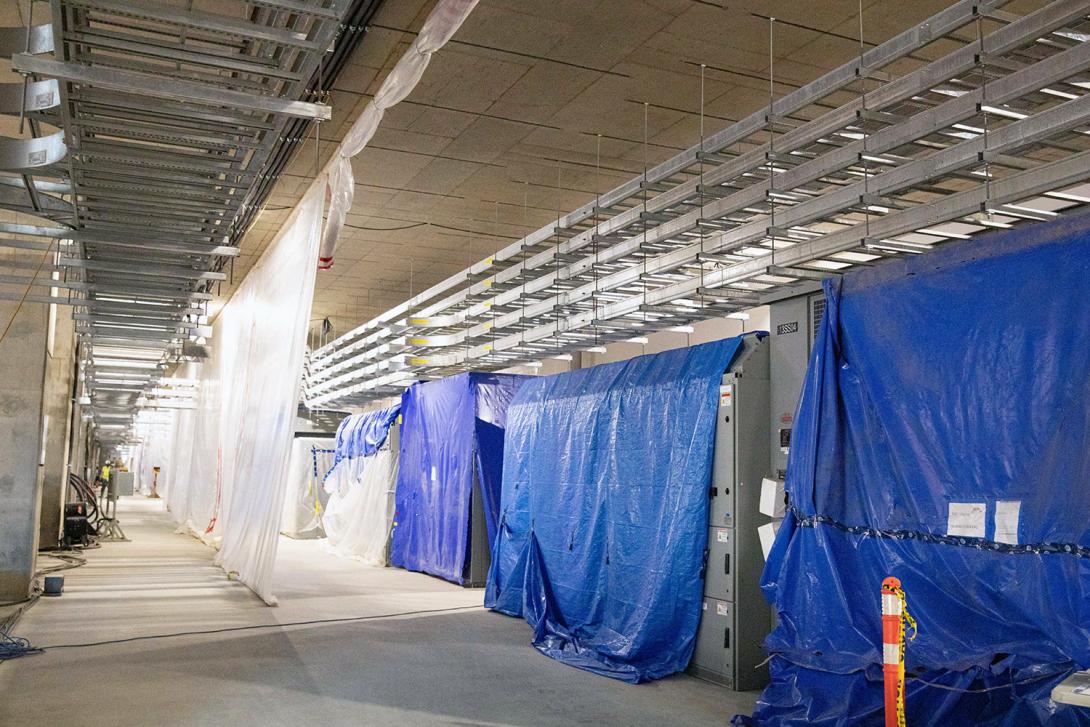 Electrical gear on the generator floor downstream, with poly wall and tarps for dust control during construction. | August 2022