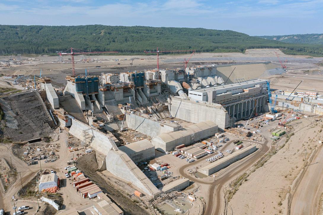 Upstream view of the spillways and penstocks, with the approach channel behind. The powerhouse and operation building is in front of the penstocks. | August 2022