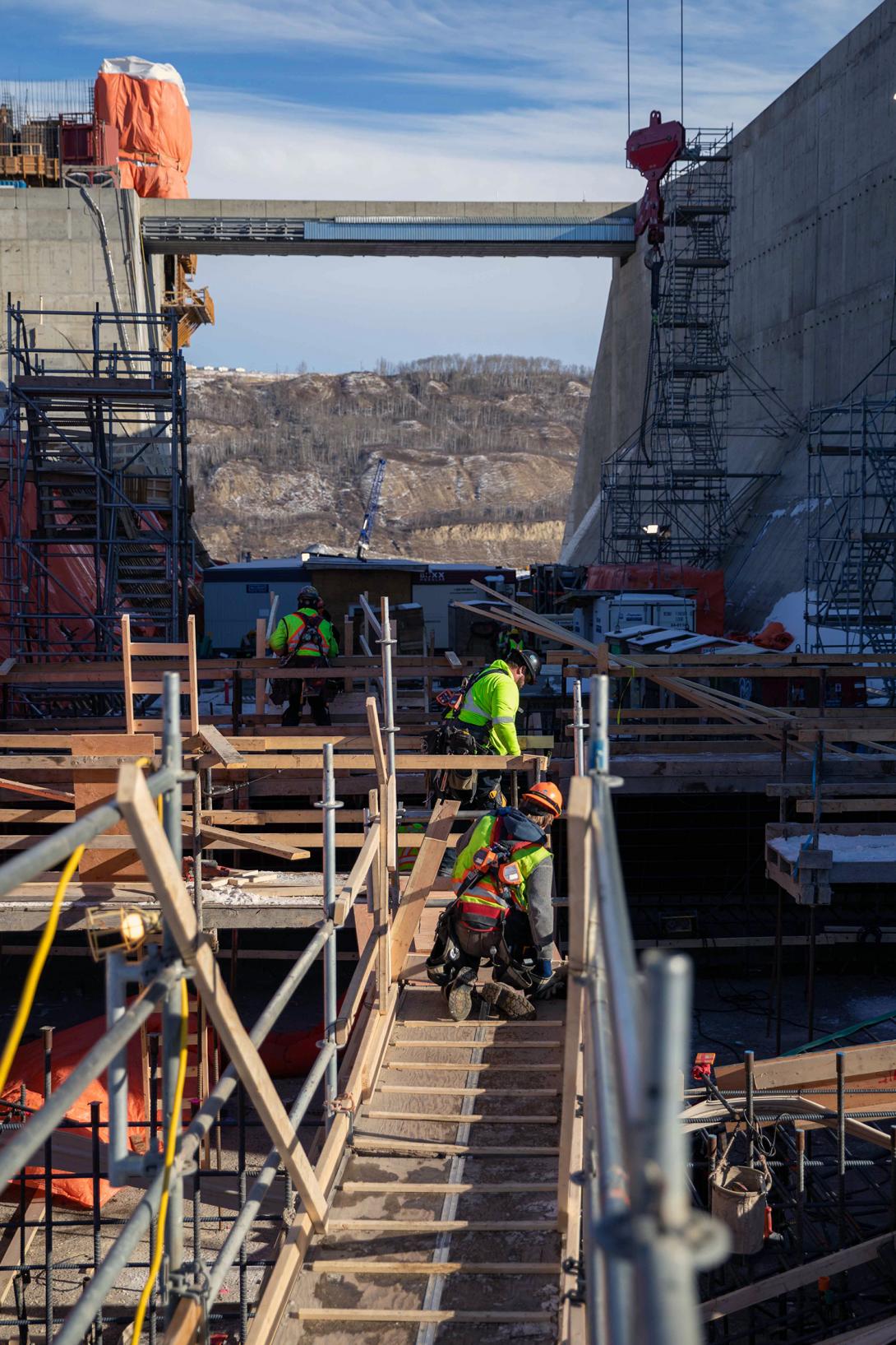 Workers build an access walkway in advance of the next concrete pour for the auxiliary spillway. | March 2023