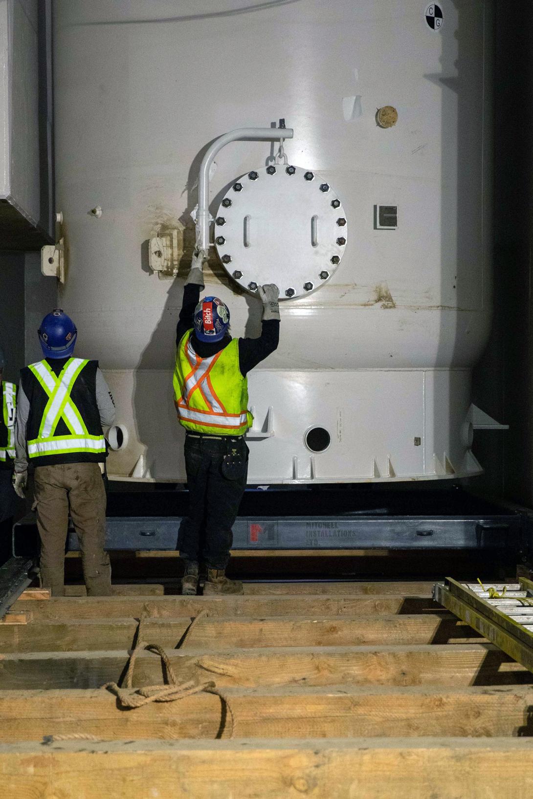 A worker guides the air receiver tank as it’s lowered into position below the powerhouse floor. | April 2023