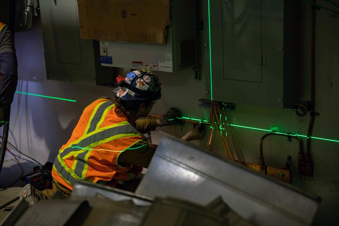 A worker uses a laser alignment system to place cables around a junction box. | April 2023