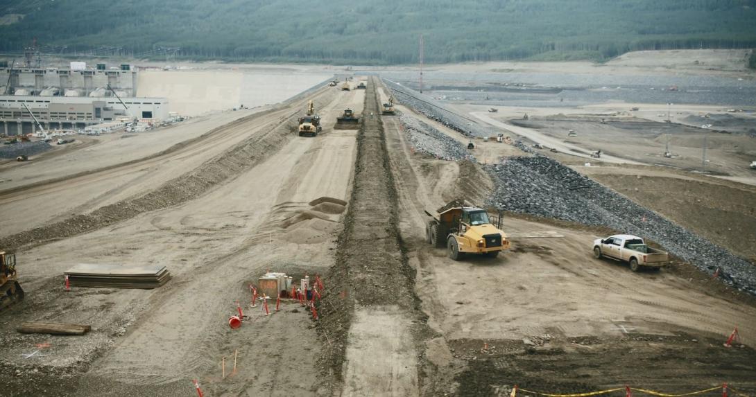 View across the earthfill dam with construction vehicles.