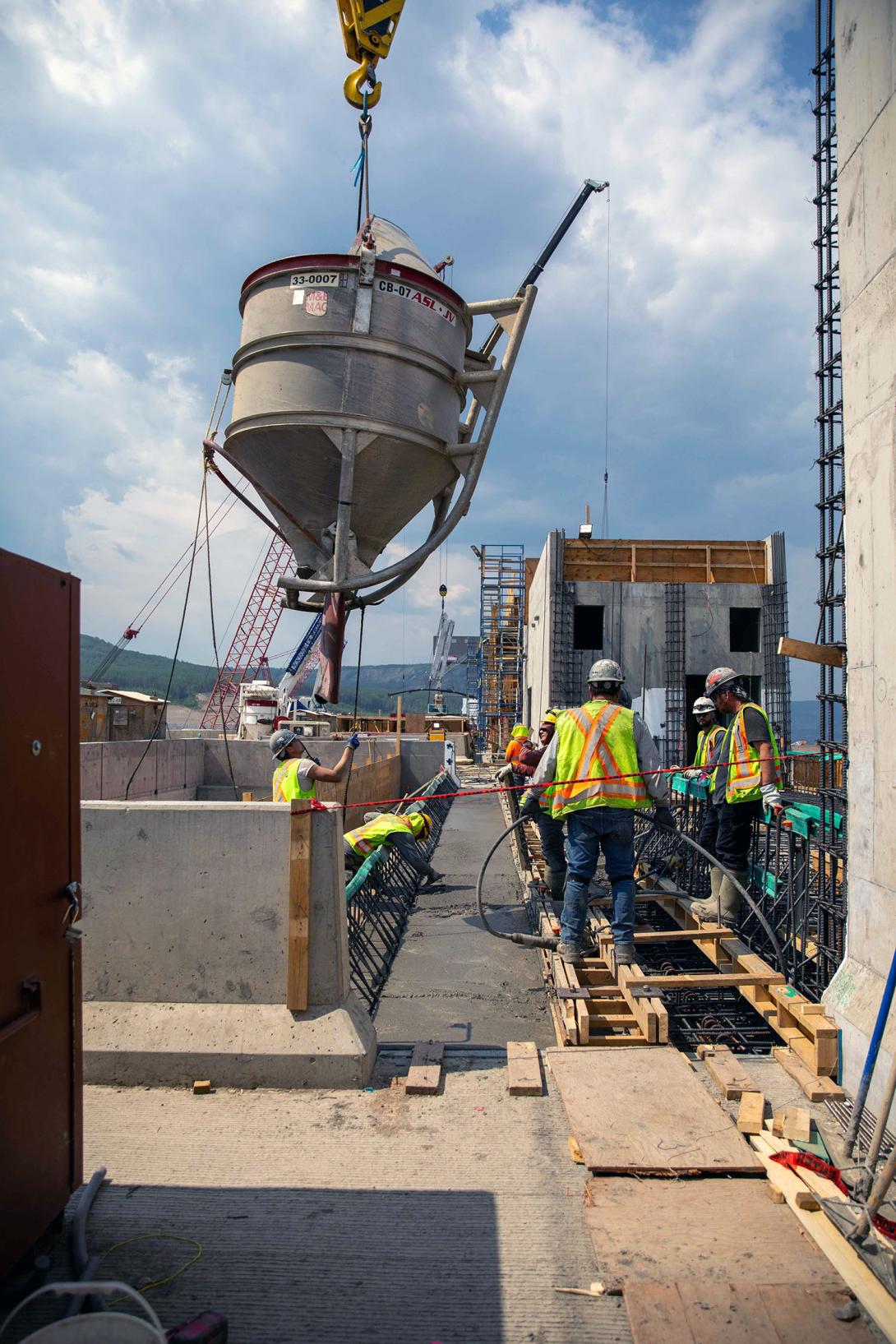 A bucket carries concrete for the top of the spillway headworks. | June 2023