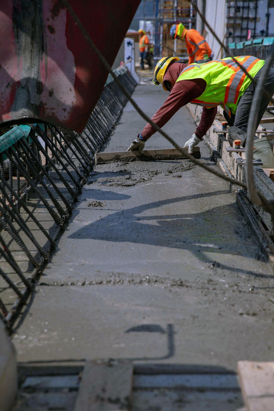 A cement mason uses a screed to level off the freshly placed concrete at the spillway headworks. | June 2023