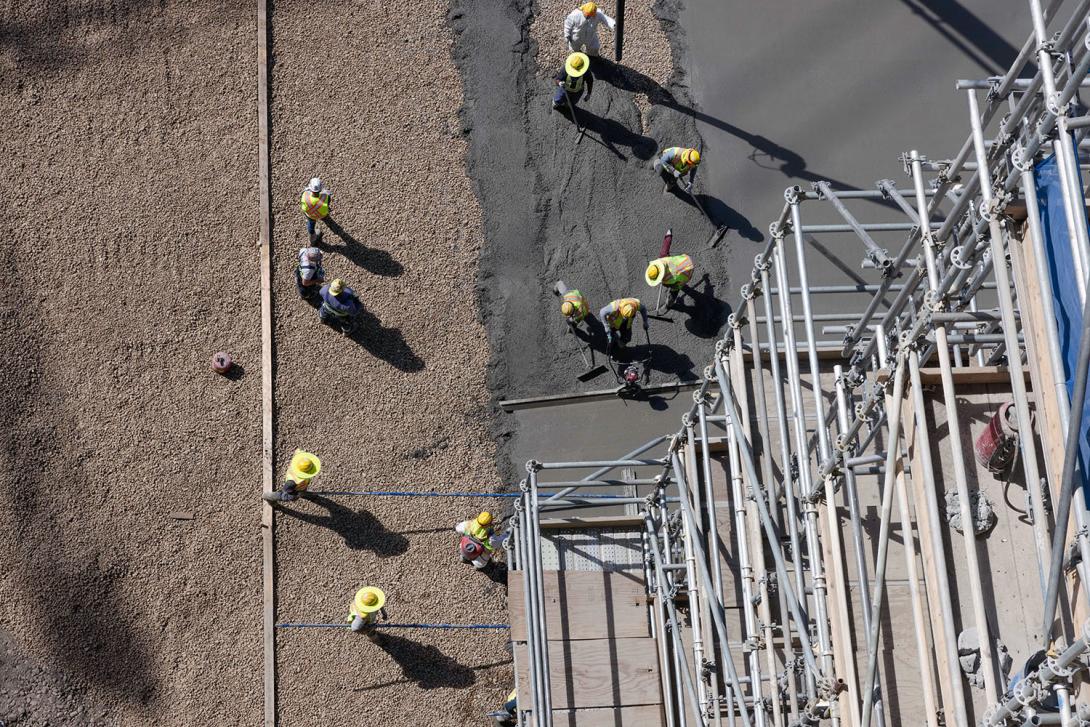 Concrete is placed in the approach channel. Workers wear safety glasses as well as special hats that drop a face shield for additional protection. | August 2023