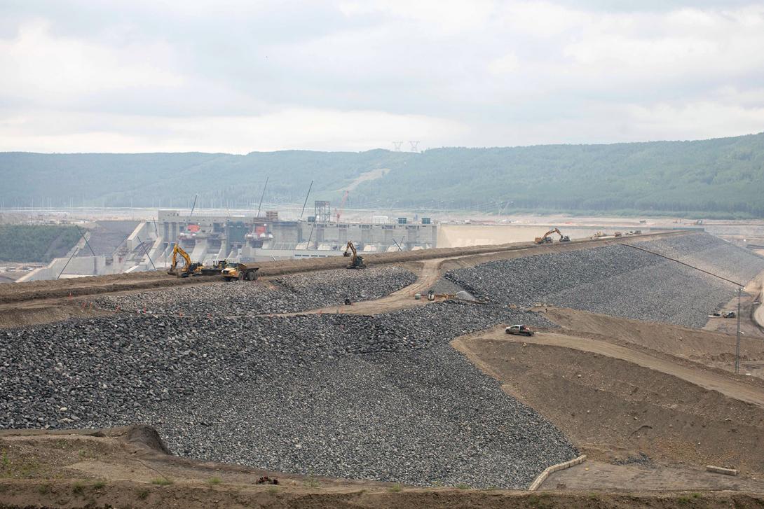 Riprap will protect the upstream shell of the dam.  At centre right, the upstream debris management ramp is being built.