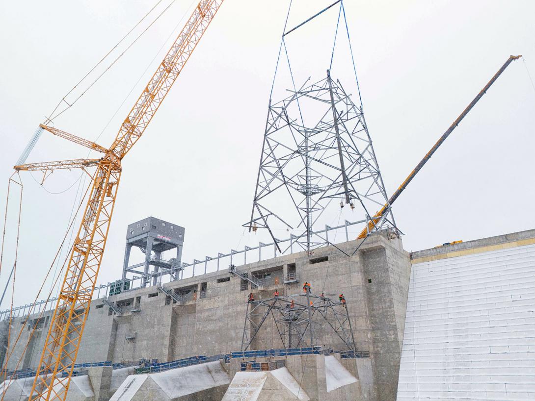 The second section of the transmission tower on unit 1 is hoisted into position and lowered onto the base section.