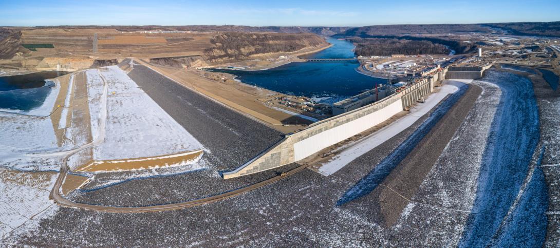 The upstream side of the completed Site C dam, dam buttress and approach channel where the reservoir flows into the intake gates and into the generator units.