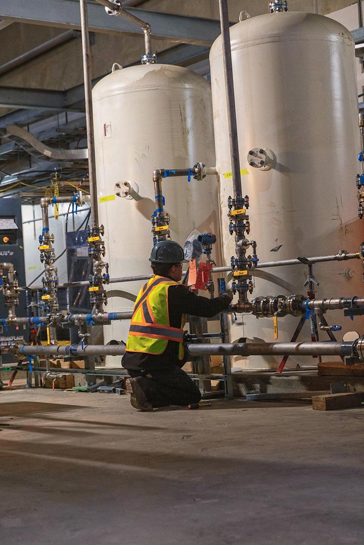 On the mechanical floor in the powerhouse, a technician confirms the piping around the two service air receiver tanks. | March 2024