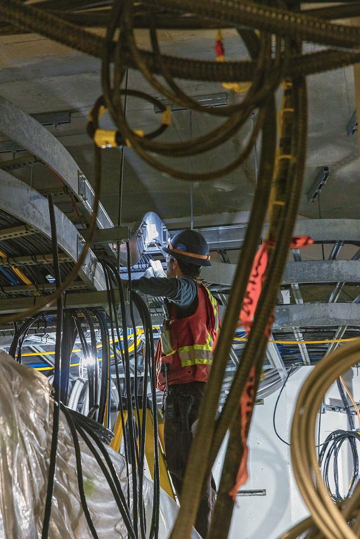 An electrician is placing and securing cables in a cable tray. There are more than 11 kilometres of cable trays to store the electrical and communication cables. | March 2024