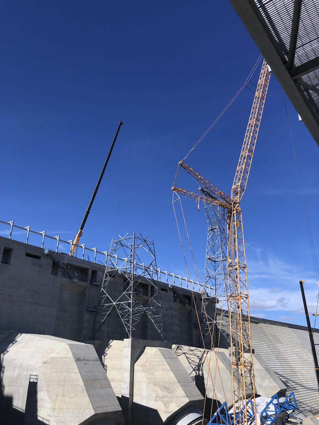 A 440-tonne crane with 177-foot boom is used to assemble the second transmission tower. Powerline technicians wait for the next section to be positioned. 