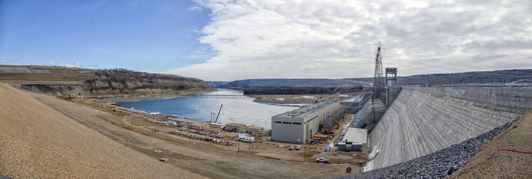 Downstream view from the dam crest of the concrete buttress wall, transformer yard, and powerhouse. | April 2025