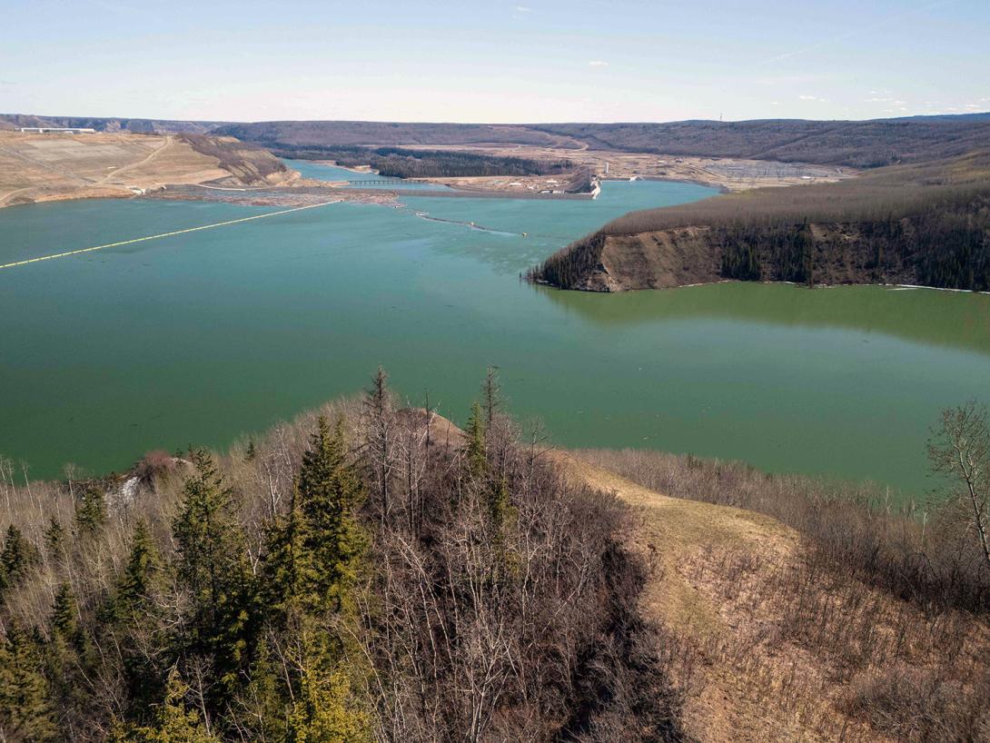 View of Site C looking downstream from the confluence of the Moberly River. The booms direct the flow of debris within the reservoir and from the Moberly River towards the dam’s north abutment,  left of centre. | April 2025