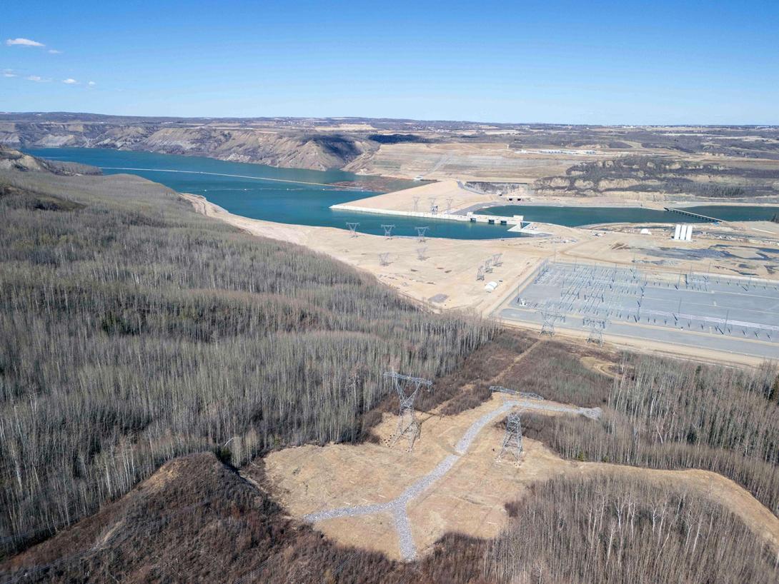 Site C’s 500 kilovolt transmission connection to the grid in foreground, with the generating station and dam across the approach channel. | April 2025